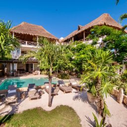 Pool and garden with palapa rooftops — Casa Coco, Isla Mujeres, Mexico
